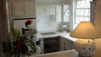 A kitchen with white cabinets, a coffee maker, and a lamp on the counter.