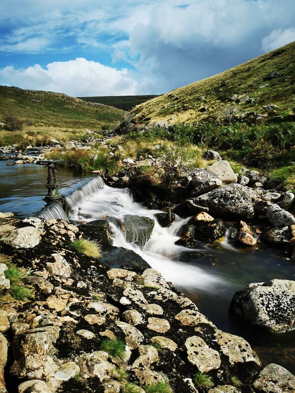 A natural landscape with a flowing stream, rocky terrain, and green hills. - Lovely cottage situated in 40 acres (Tavistock)
