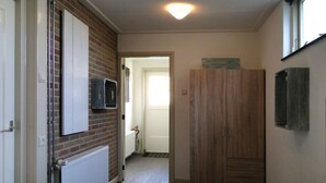 Una habitación con dos camas, una pared de ladrillo, un armario de madera y un televisor fijado en la pared.