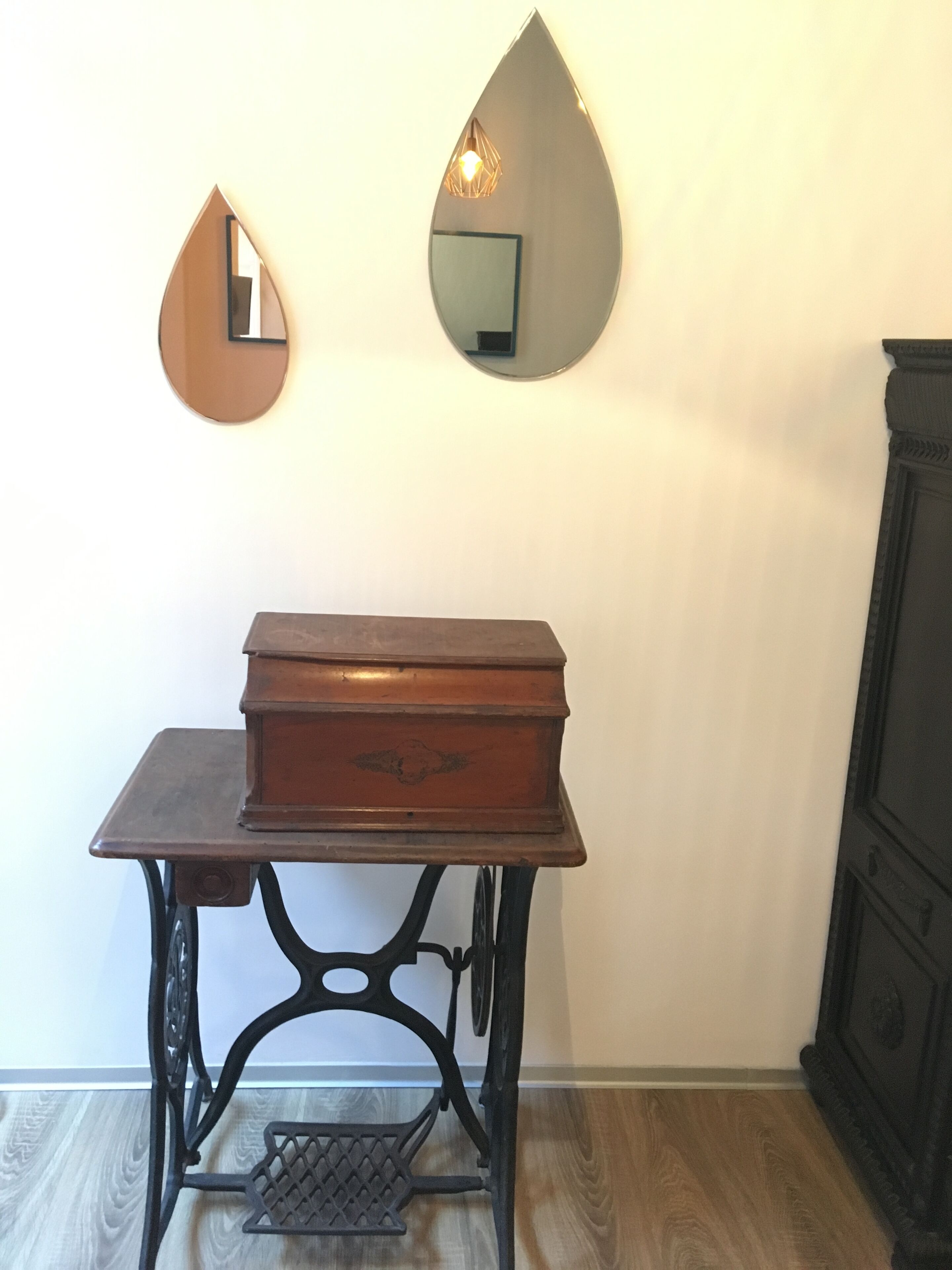 Une table en bois avec un tiroir, un miroir et un luminaire décoratif fixé au mur.