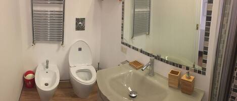 A bathroom with a bidet, a toilet, a sink, and a mirror.