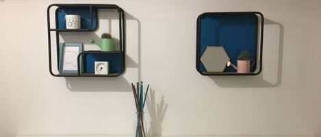 Two wall-mounted shelves with various items including a clock, a watering can, and a potted plant.