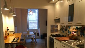 Une cuisine moderne avec des meubles blancs, un plan de travail en bois et un coin repas comprenant une table et des chaises.