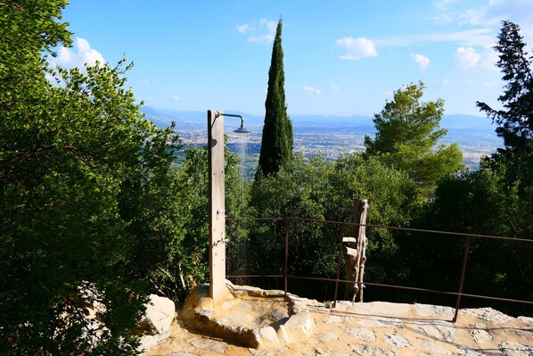 A stone staircase leading to a viewing platform with a metal railing, overlooking a cityscape and distant mountains.
