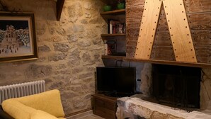 Ein gemütliches Wohnzimmer mit einer Steinwand, einem Kamin, einem gelben Sofa und einem Fernseher.