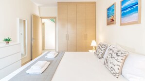 A hotel room with a bed, a bedside table with a lamp, a large wardrobe, and two framed pictures on the wall.