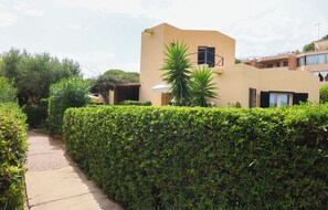A pathway leading to a building with a modern design, surrounded by well-maintained hedges.