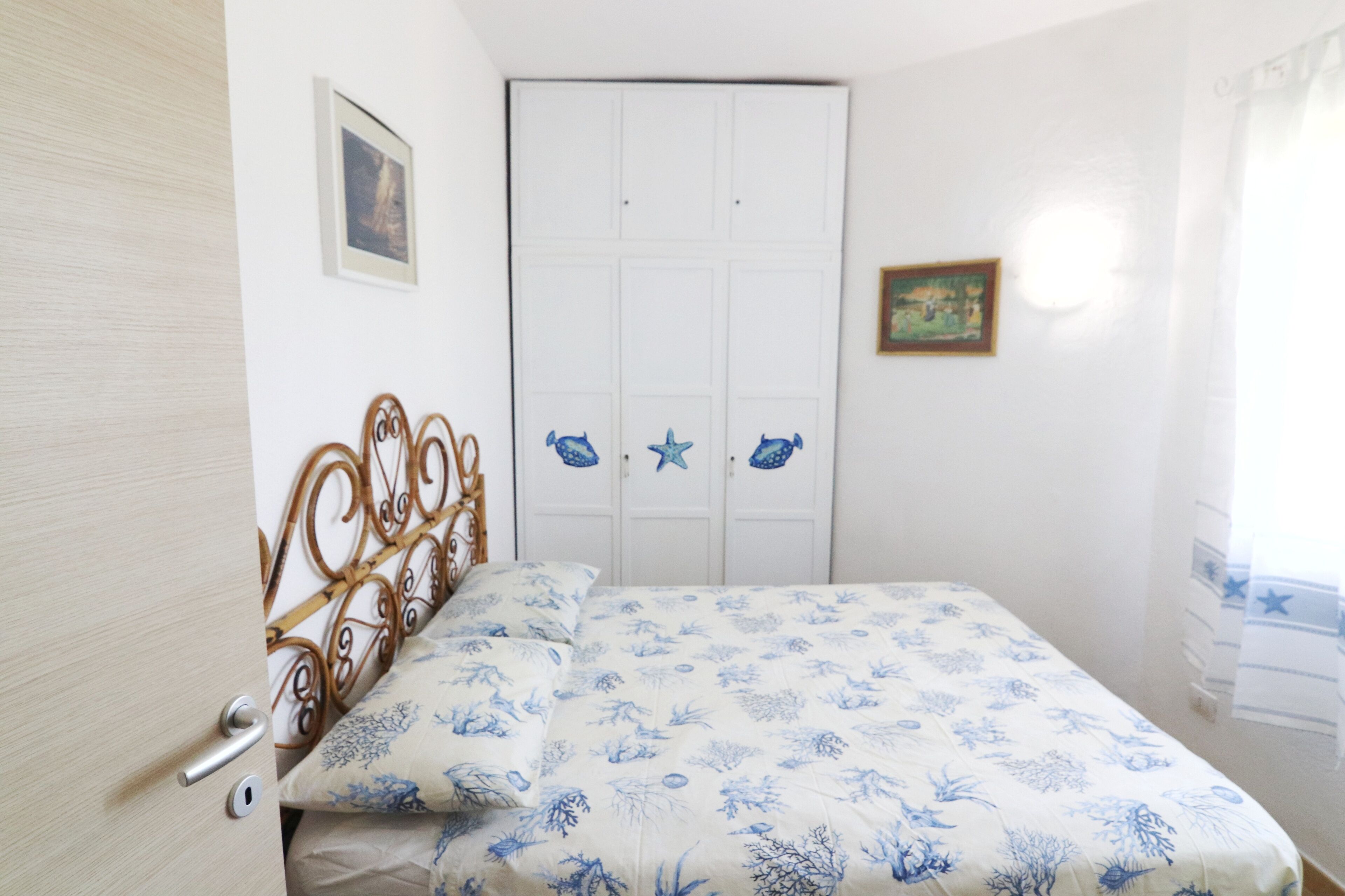 A bedroom with a bed, a door, and a wall with a framed picture.