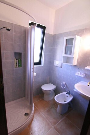 Un baño con ducha, inodoro, bidé y lavabo.