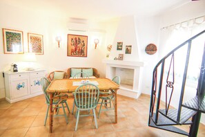A dining area with a wooden table and chairs, a white cabinet, and wall-mounted artwork.