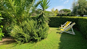 A well-maintained garden with a lawn, a yellow lounge chair, and a variety of green plants.