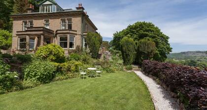Suuri Edwardian huvila, joka sijaitsee kypsässä metsäpuutarhassa, panoraamanäköalalla