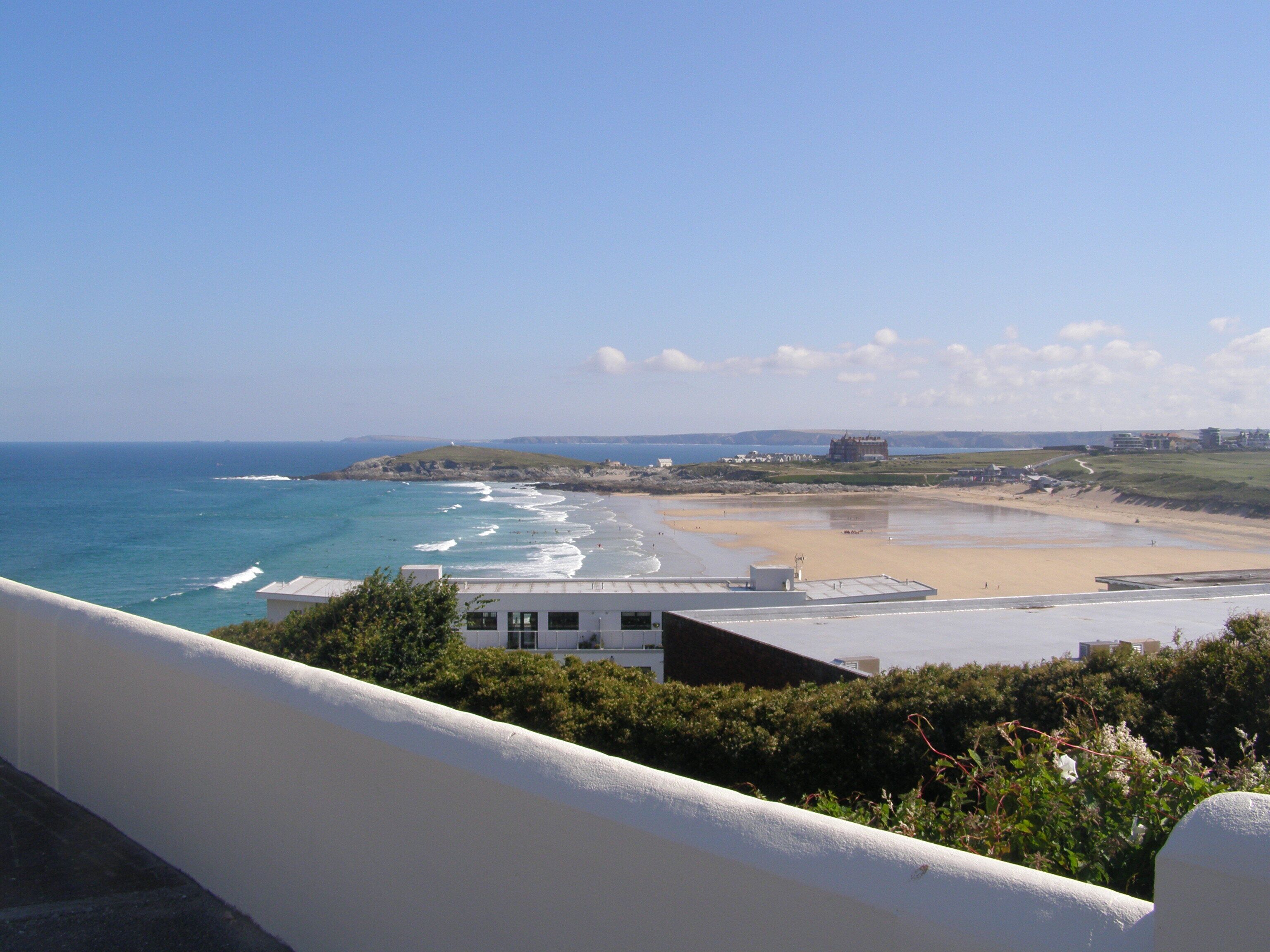 A coastal view with a beach, ocean, and buildings in the distance.