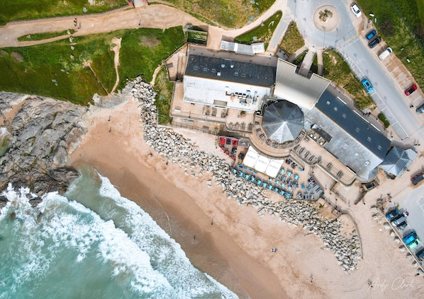 An aerial view of a coastal hotel with a beach area, a parking lot, and a roundabout. - Summer - Perfect Place to enjoy all that Newquay offers for a Summer Break (Newquay)