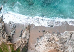 A coastal landscape with rocky cliffs and a sandy beach. - Summer - Perfect Place to enjoy all that Newquay offers for a Summer Break (Newquay)