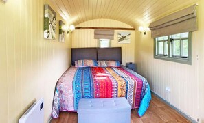 Ein Schlafzimmer mit Bett, Nachttisch, Fenster und Wandbildern.