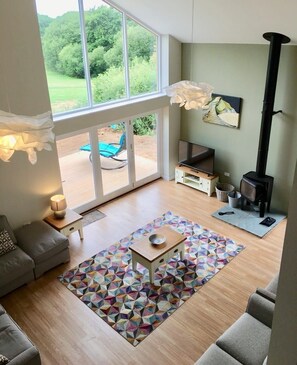 A living room with a sofa, a coffee table, a TV, a fireplace, and a view of the outdoors.