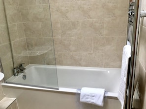 A modern bathroom with a glass-enclosed shower, a bathtub, and a towel rack.