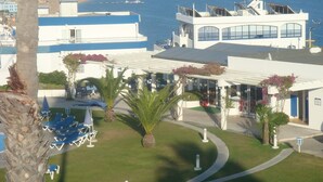 Et hotel med poolområde, palmer og havudsigt.
