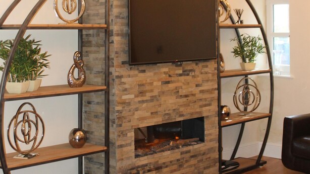 Ein Wohnzimmer mit Kamin, einer Kristallleuchter und einem an der Wand befestigten Fernseher.