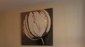 Ein ordentlich bezogenes Bett mit Kopfteil, einer Nachttischlampe und einem Bild an der Wand.