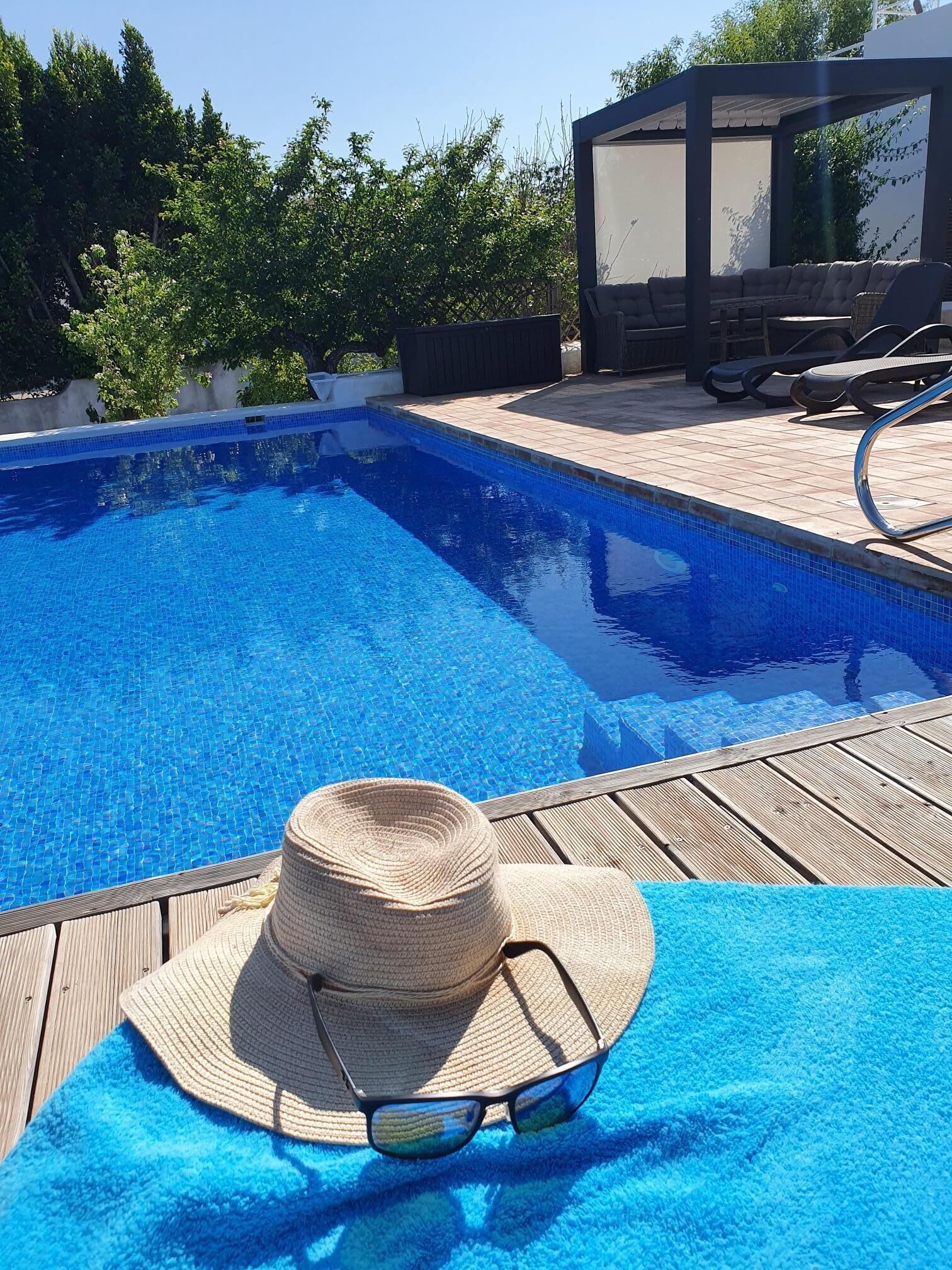 Une piscine avec des chaises longues et un espace salon abrité.