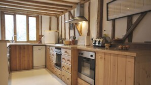 Una cocina con armarios de madera, lavavajillas, horno y fregadero.