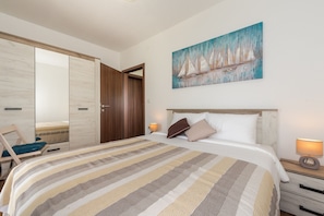 A bedroom with a bed, a nightstand, a chair, a wardrobe, and a painting on the wall. - New Villa for 8 people with spectacular view (Potpican)