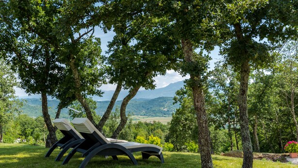 A grassy area with two lounge chairs under trees, overlooking a scenic landscape with hills and a body of water. - New Villa for 8 people with spectacular view (Potpican)