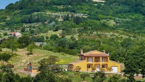 A yellow villa with a large balcony, surrounded by lush greenery and a hilltop church. - New Villa for 8 people with spectacular view (Potpican)