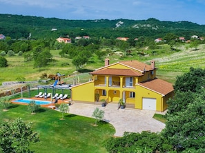 A yellow villa with a swimming pool, a covered patio, and a view of a green hillside with other houses. - New Villa for 8 people with spectacular view (Potpican)