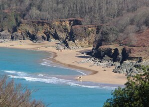 Una spiaggia costiera con scogliere rocciose, acqua cristallina blu e una battigia sabbiosa.