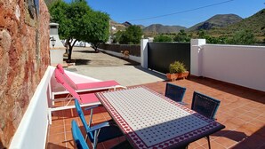 An outdoor patio with a table and chairs, a potted plant, and a view of the mountains. - Beautiful home in paradise three minutes from the best virgin beaches (Nijar)