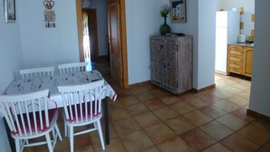 A dining area with a white table and chairs, a cabinet with a vase, and a kitchen area visible through an open door. - Beautiful home in paradise three minutes from the best virgin beaches (Nijar)