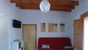 A room with a red sofa, wooden beams, a white cabinet, and a television on the wall. - Beautiful home in paradise three minutes from the best virgin beaches (Nijar)