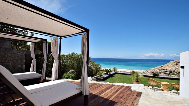 A wooden deck with a white lounge chair, a covered seating area, and a view of the beach and ocean. - Exclusive villa on the beach front. FREE WIFI (Tarifa)