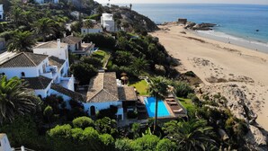 A coastal villa with a private pool, surrounded by lush greenery and a beach. - Exclusive villa on the beach front. FREE WIFI (Tarifa)