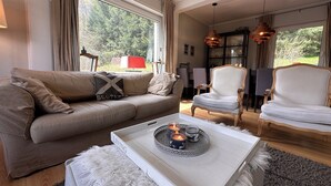 Ett vardagsrum med en beige soffa, en vit fåtölj och ett soffbord med ljus.