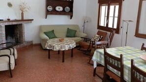 Un soggiorno accogliente con un divano, un tavolino rotondo, un tavolo da pranzo con sedie, un camino e una finestra.