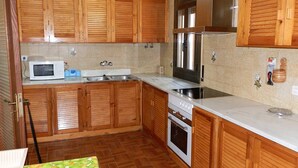 Una cucina con mobili in legno, un forno a microonde, un fornello e un frigorifero.