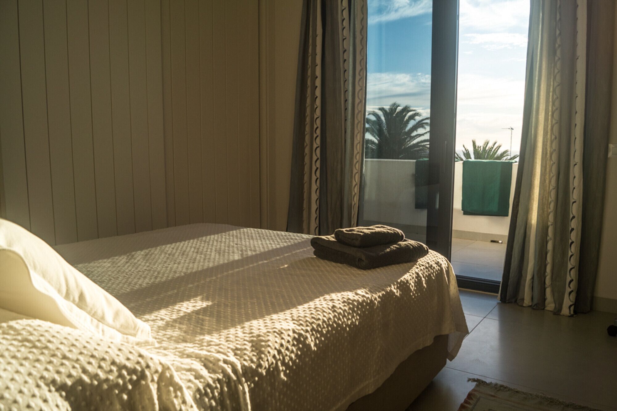 A bedroom with a bed, curtains, and a view of the outdoors.