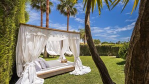 A private outdoor bedroom with a canopy bed, surrounded by palm trees and a well-maintained lawn. - Villa Dome OCV - Private Heated Pool (Albufeira)