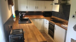 A kitchen with wooden countertops, white cabinets, a black microwave, and a built-in oven. - Traditional Dales Cottage with stunning views,  (Newbiggin, Bishopdale)