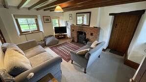 A cozy living room with a fireplace, two sofas, a TV, and a bookshelf. - Traditional Dales Cottage with stunning views,  (Newbiggin, Bishopdale)