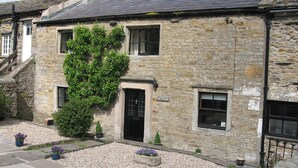 A stone building with a black door and windows, a sign reading "Westbrook House", and a gravel driveway with potted plants. - Traditional Dales Cottage with stunning views,  (Newbiggin, Bishopdale)