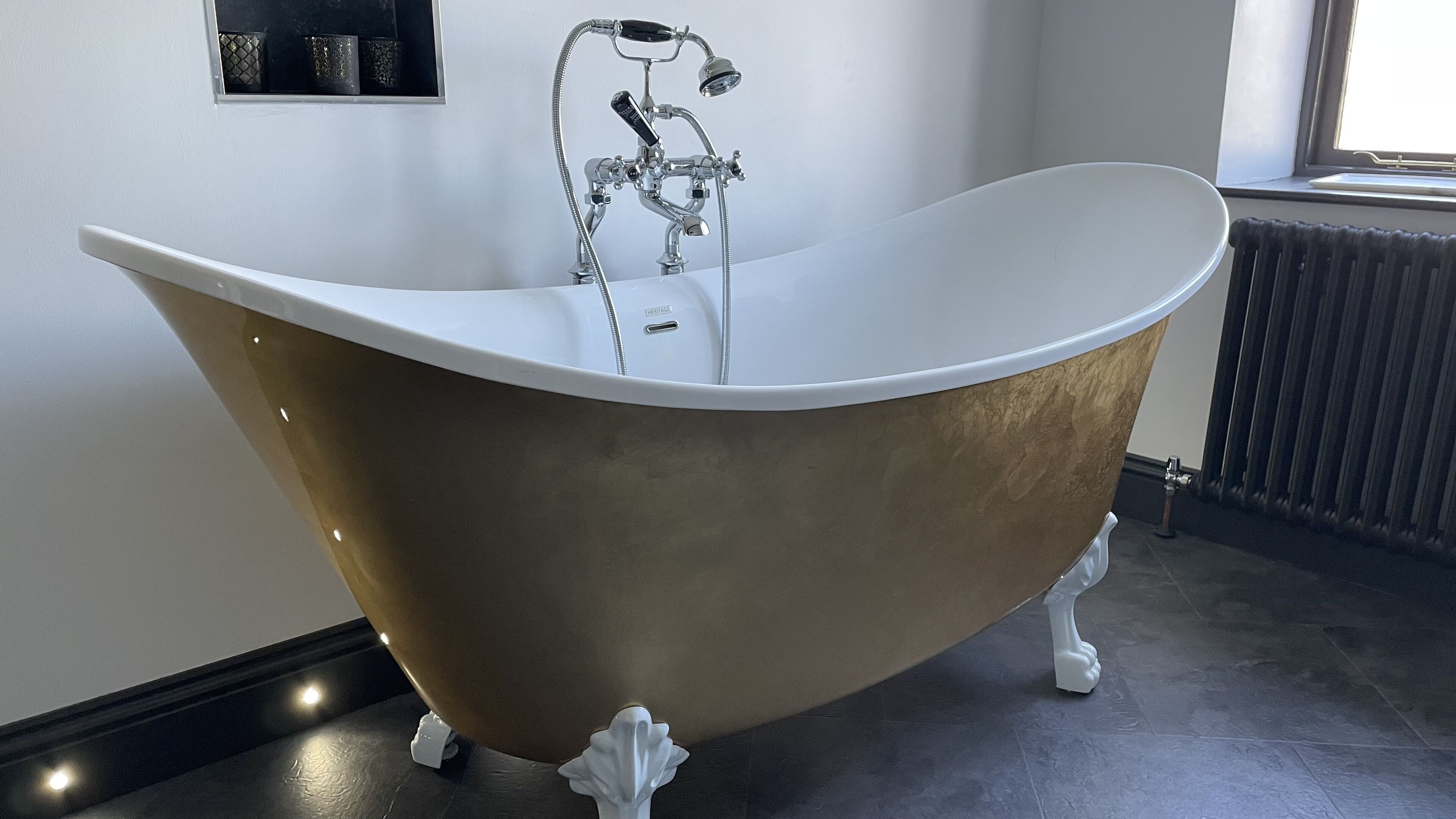 A freestanding bathtub with a curved design, a single faucet, and a small shelf above it.