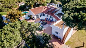 Una casa grande con piscina, zona de estar exterior y vistas al mar.
