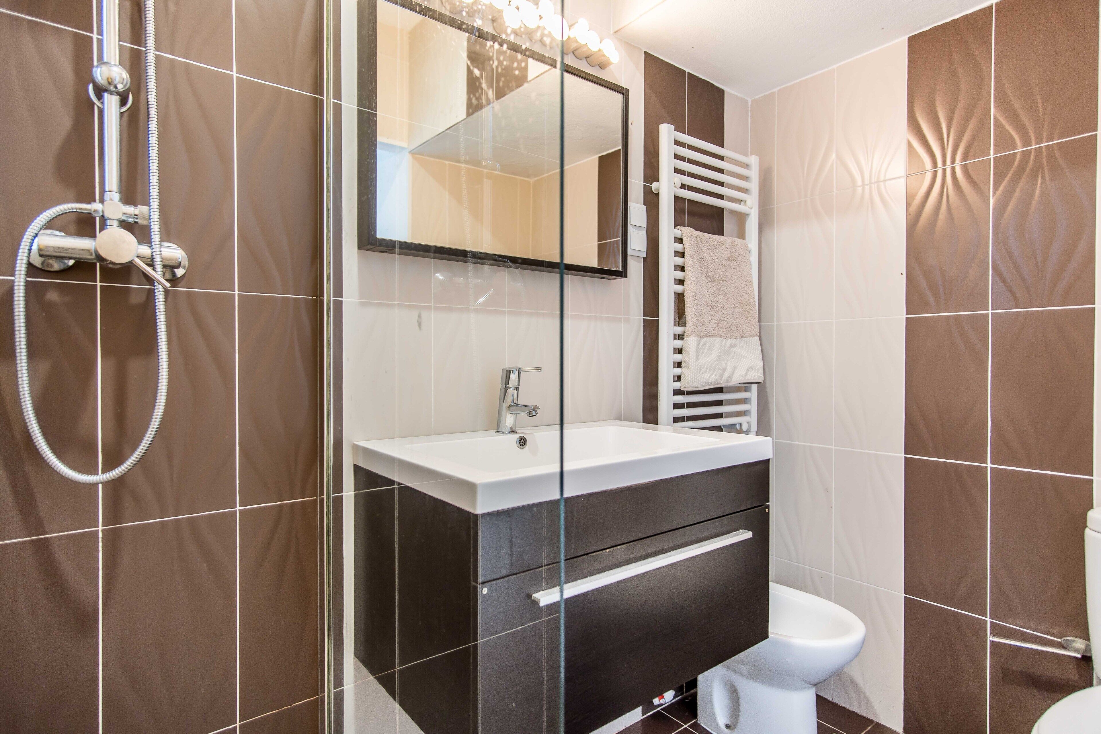 Un baño moderno con cabina de ducha de vidrio, lavamanos blanco y retrete.