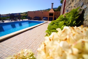 A swimming pool with lounge chairs and a brick building in the background.