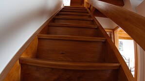 Un escalier en bois, doté d’une rampe, qui mène à un palier avec une porte et une fenêtre.